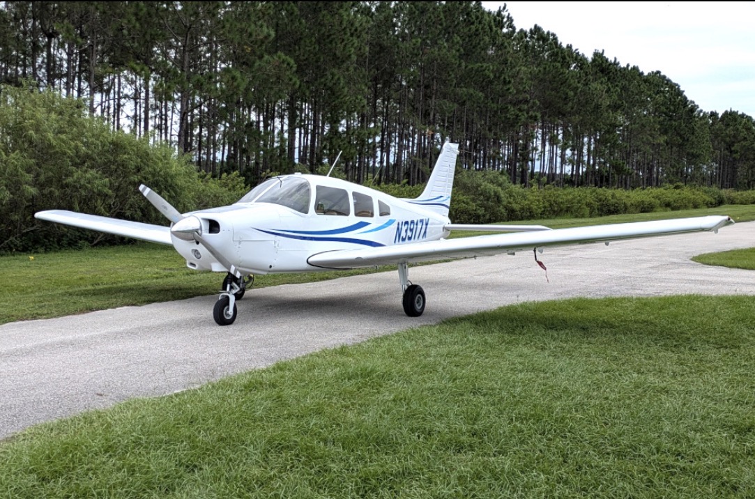 Piper PA-28-151 parked beside a grass strip
